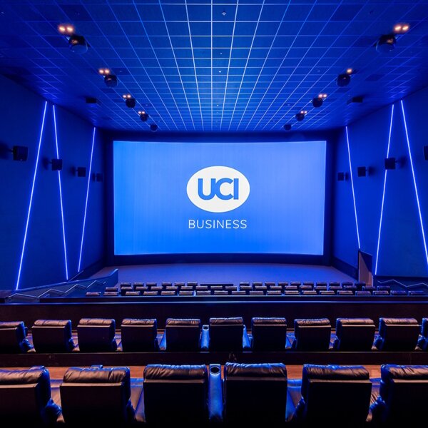 Bild eines leeren Kinosaals mit Blick auf die Leinwand, auf der "UCI Business" steht